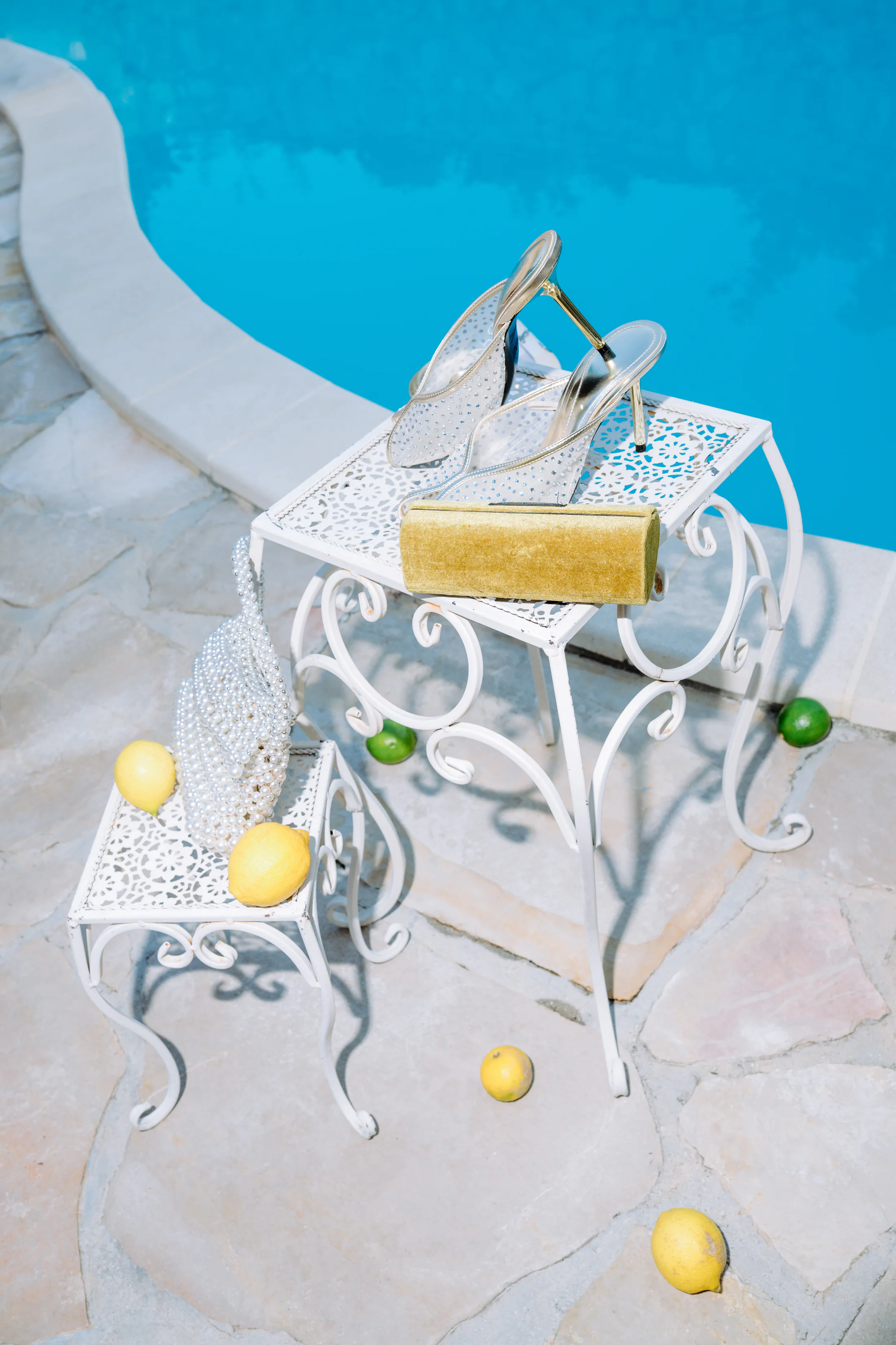 Silver bridal heels and gold clutch styled beside a swimming pool