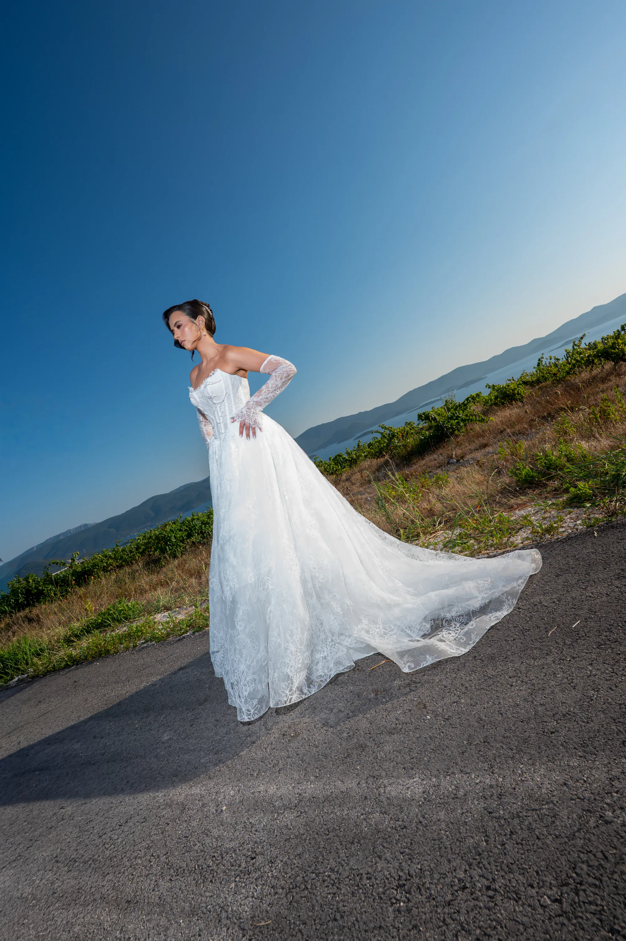 Bride standing on a mountain road beside a vineyard