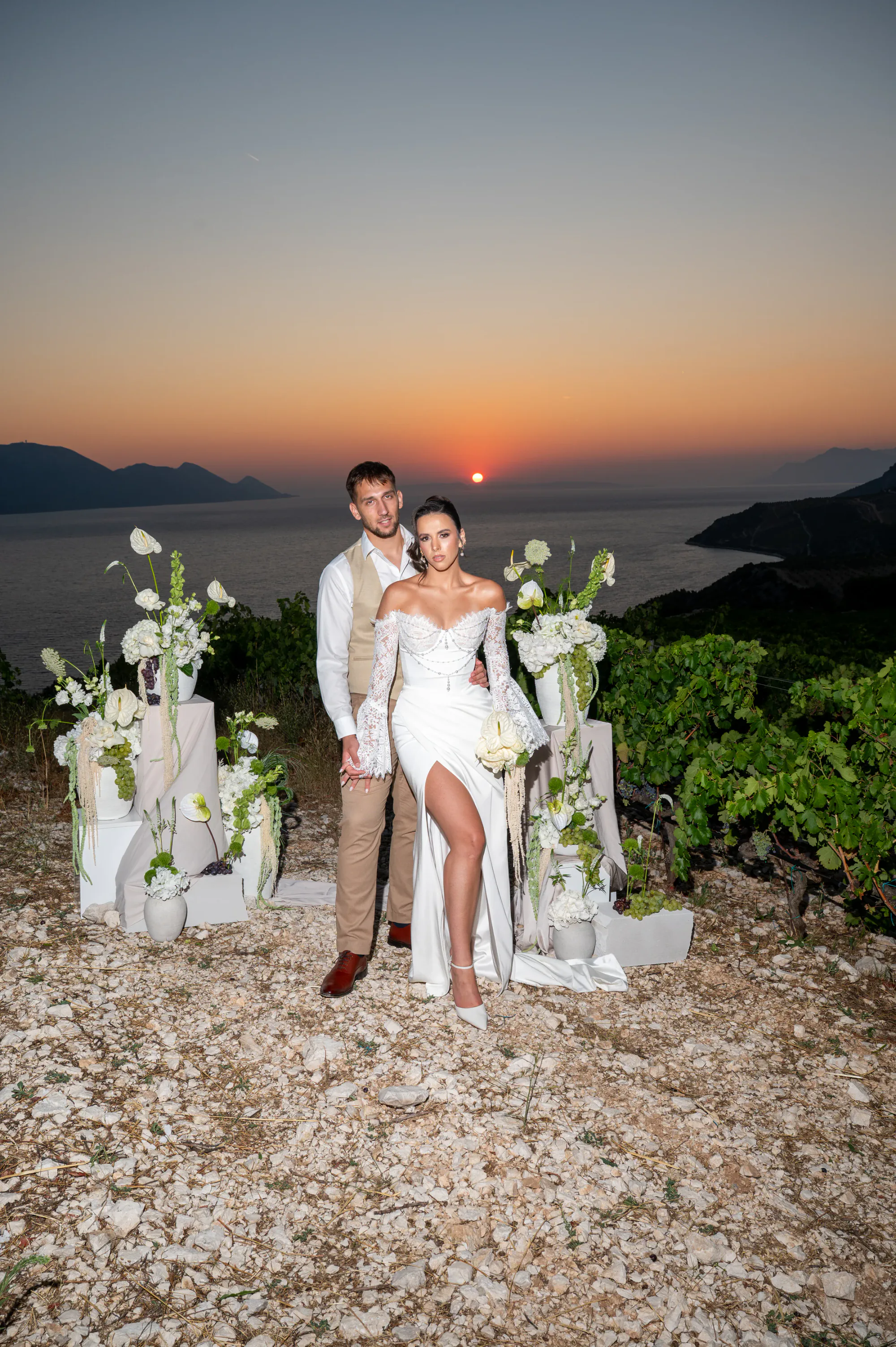 Bride and groom among white floral arrangements at sunset