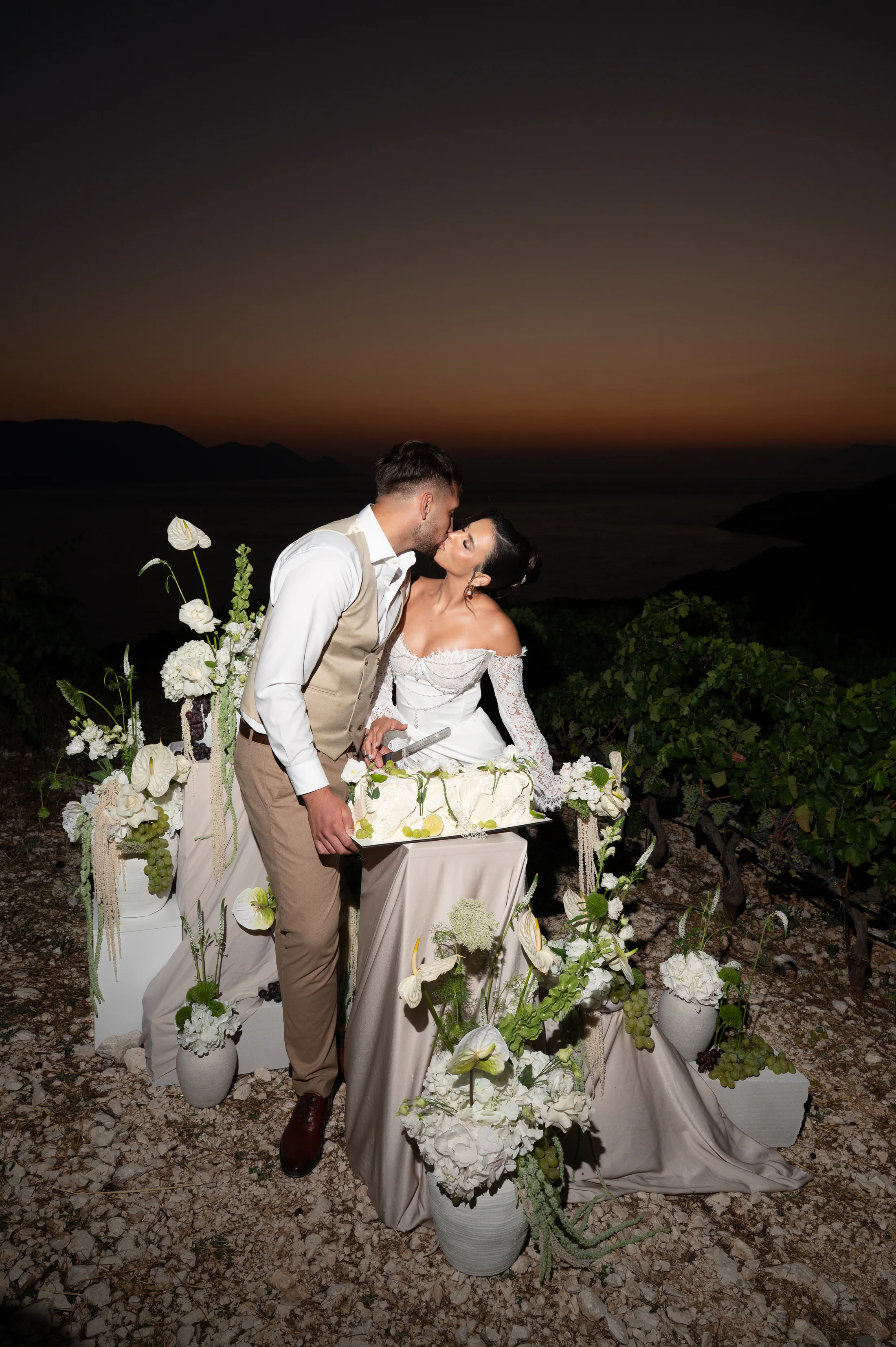 Bride and groom sharing a kiss beside an editorial wedding cake