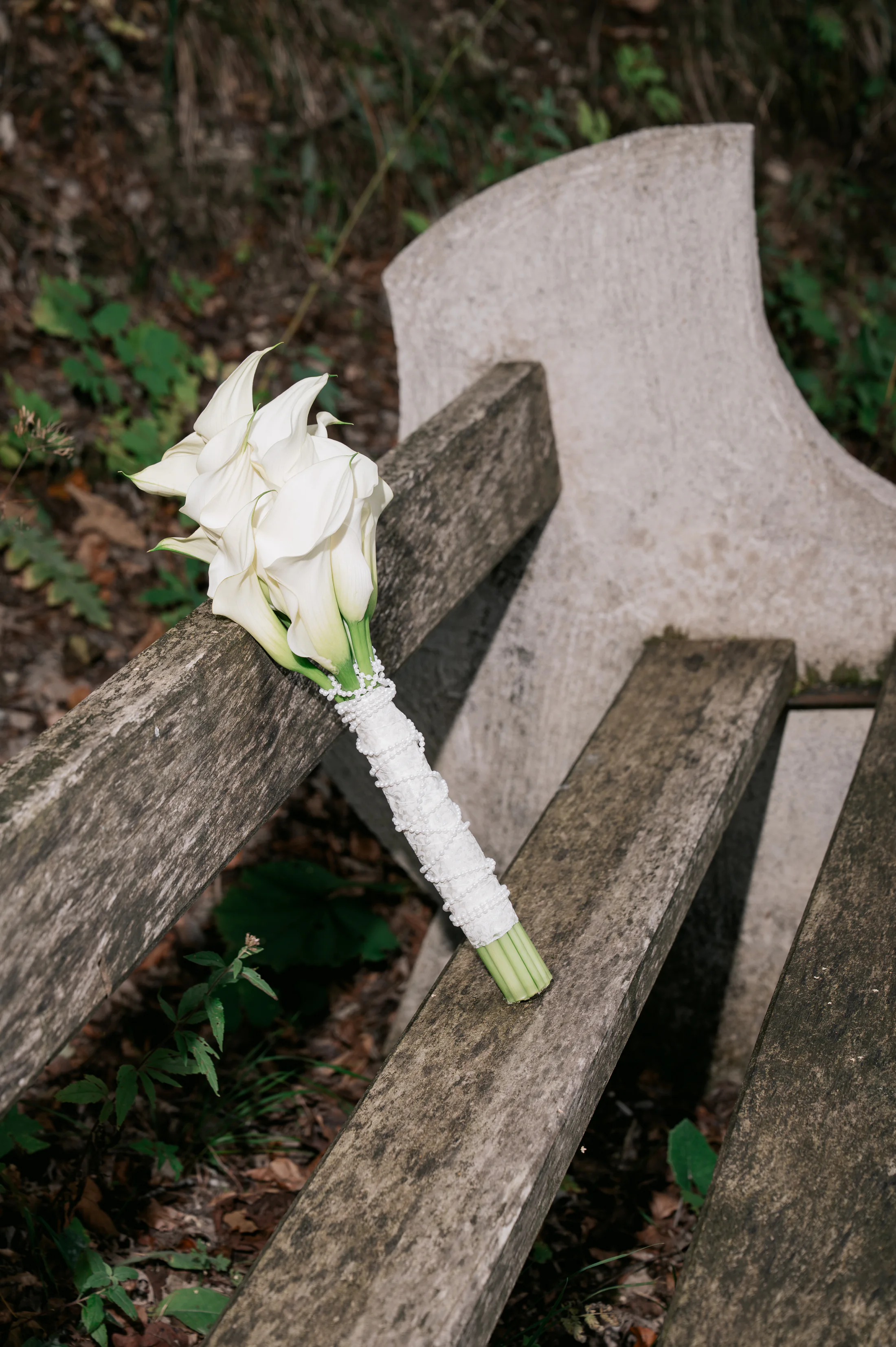 White calla lily bridal bouquet on a wooden bench